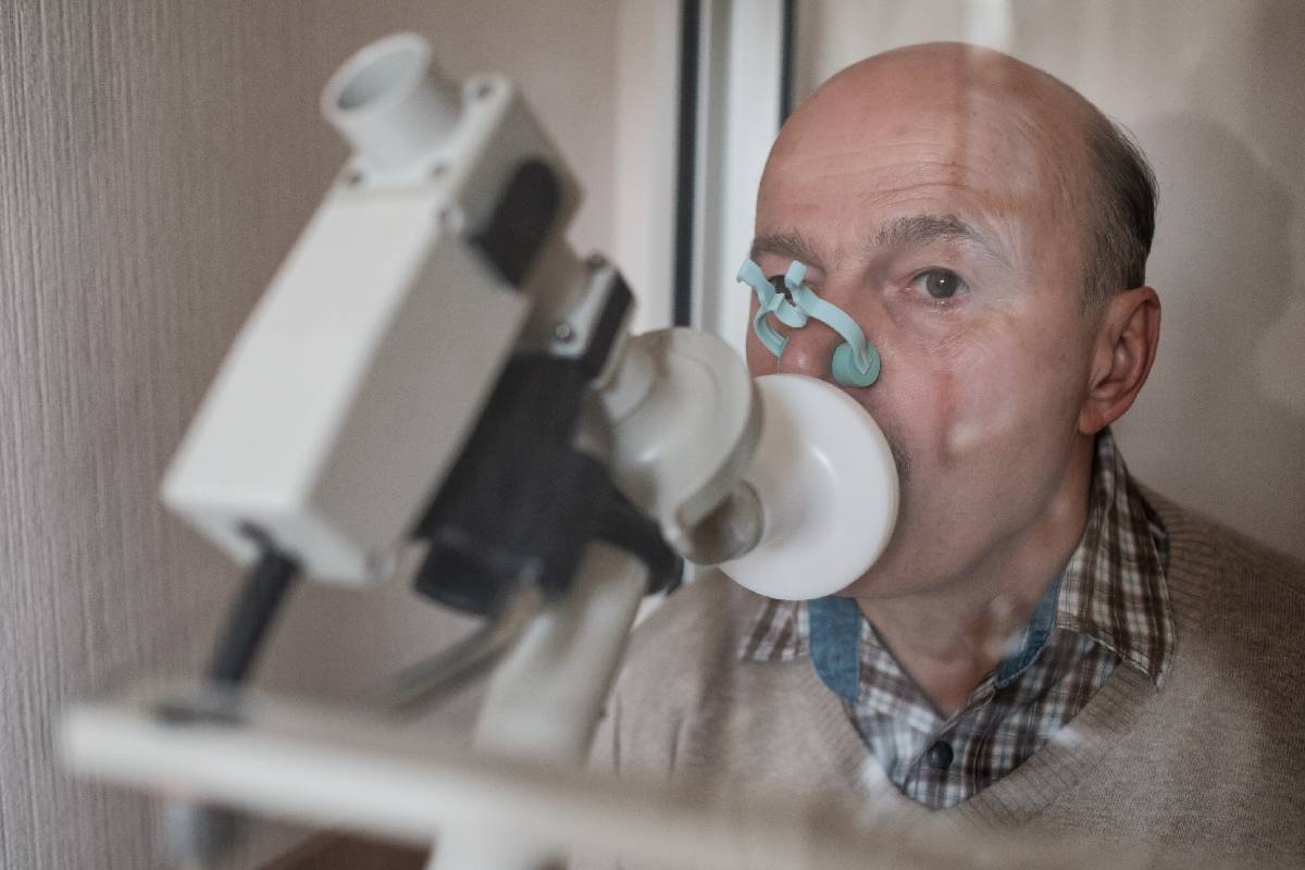 Senior hispanic man man testing breathing function by spirometry. Diagnosis of respiratory function in pulmonary disease